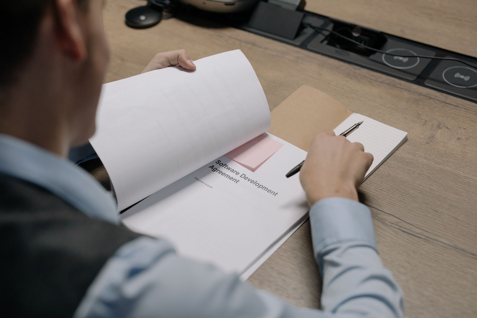 Iemand aan een bureau leest een contract voor een softwareopdracht door
