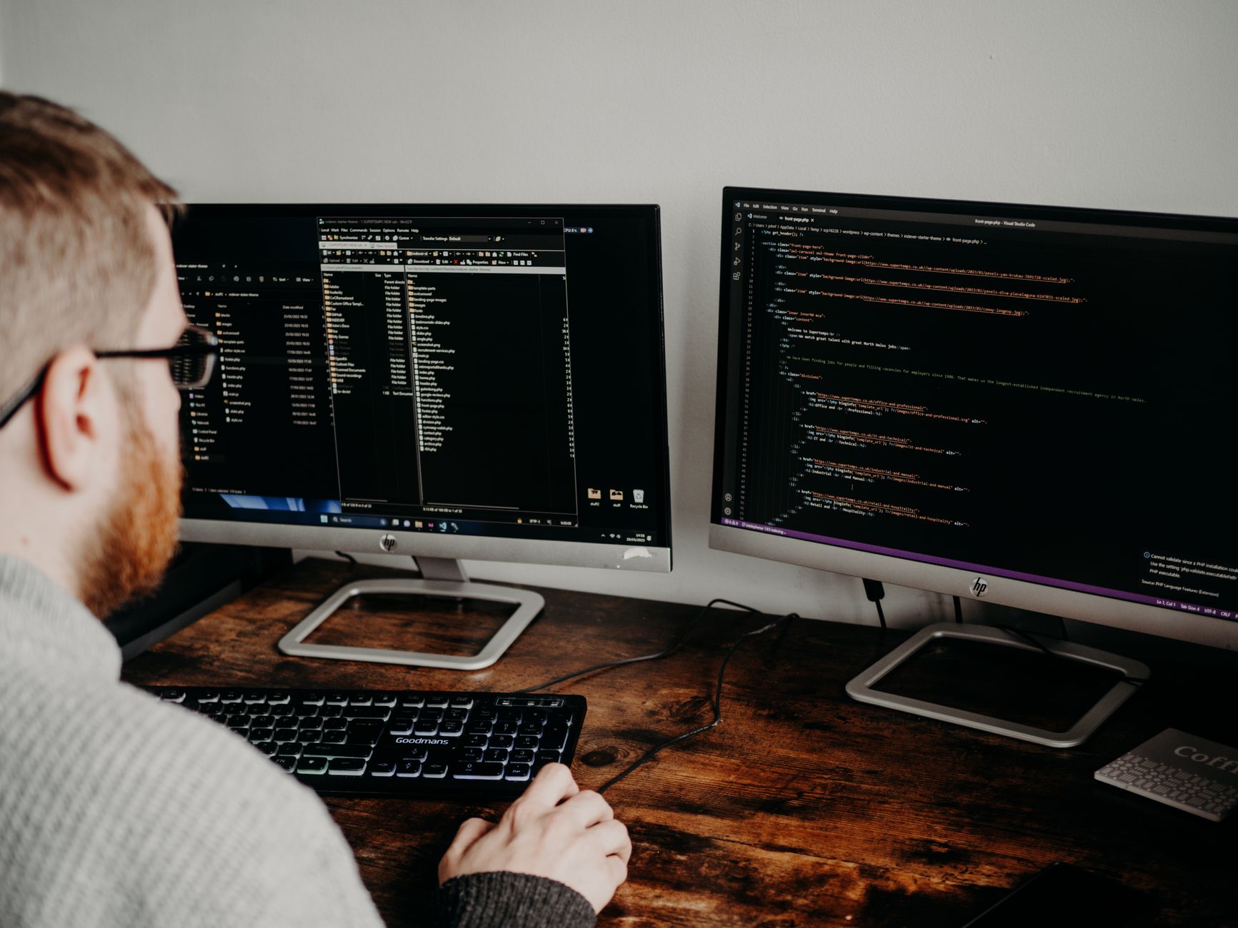Een ontwikkelaar werkt aan code op twee schermen in een thuiskantoor