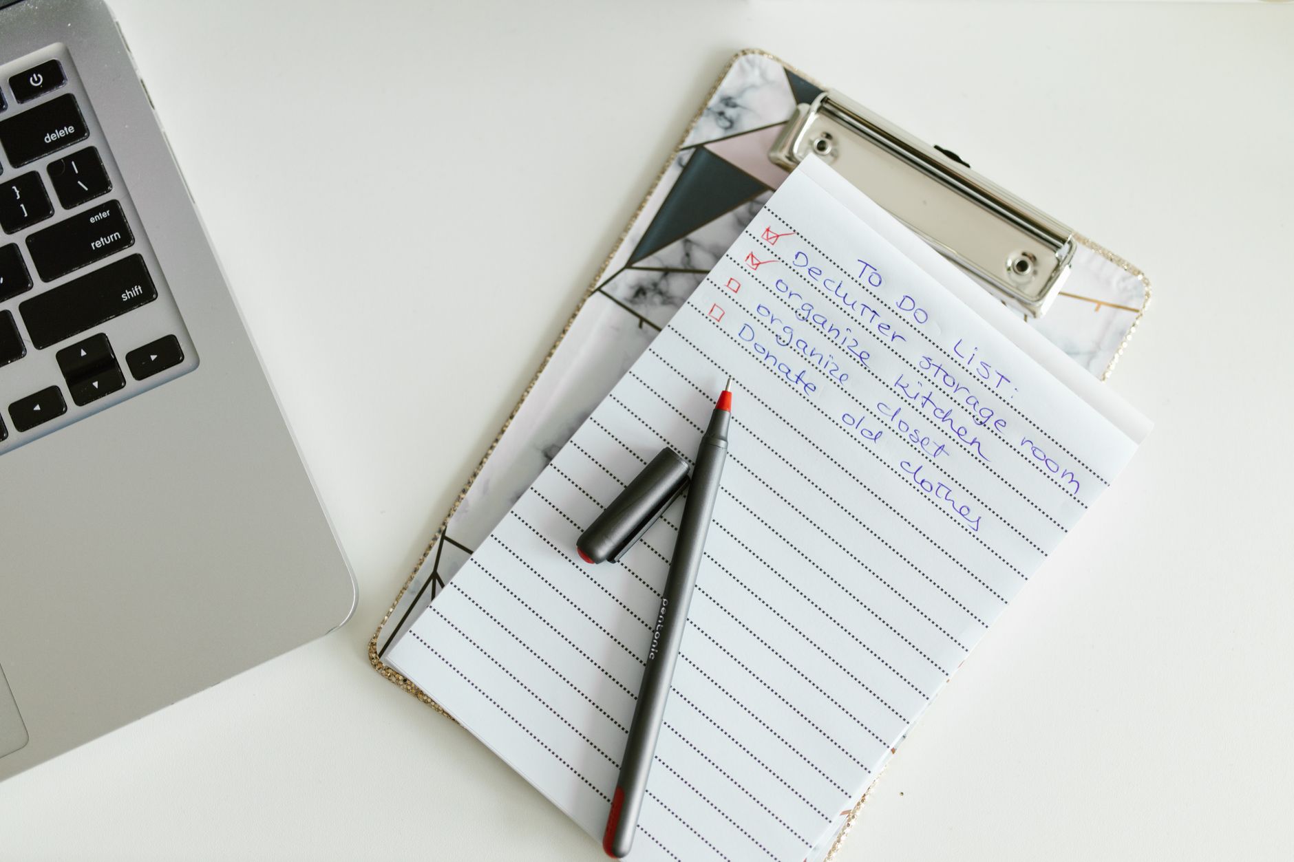 Een klembord met een afvinklijst ligt naast een laptop en een pen