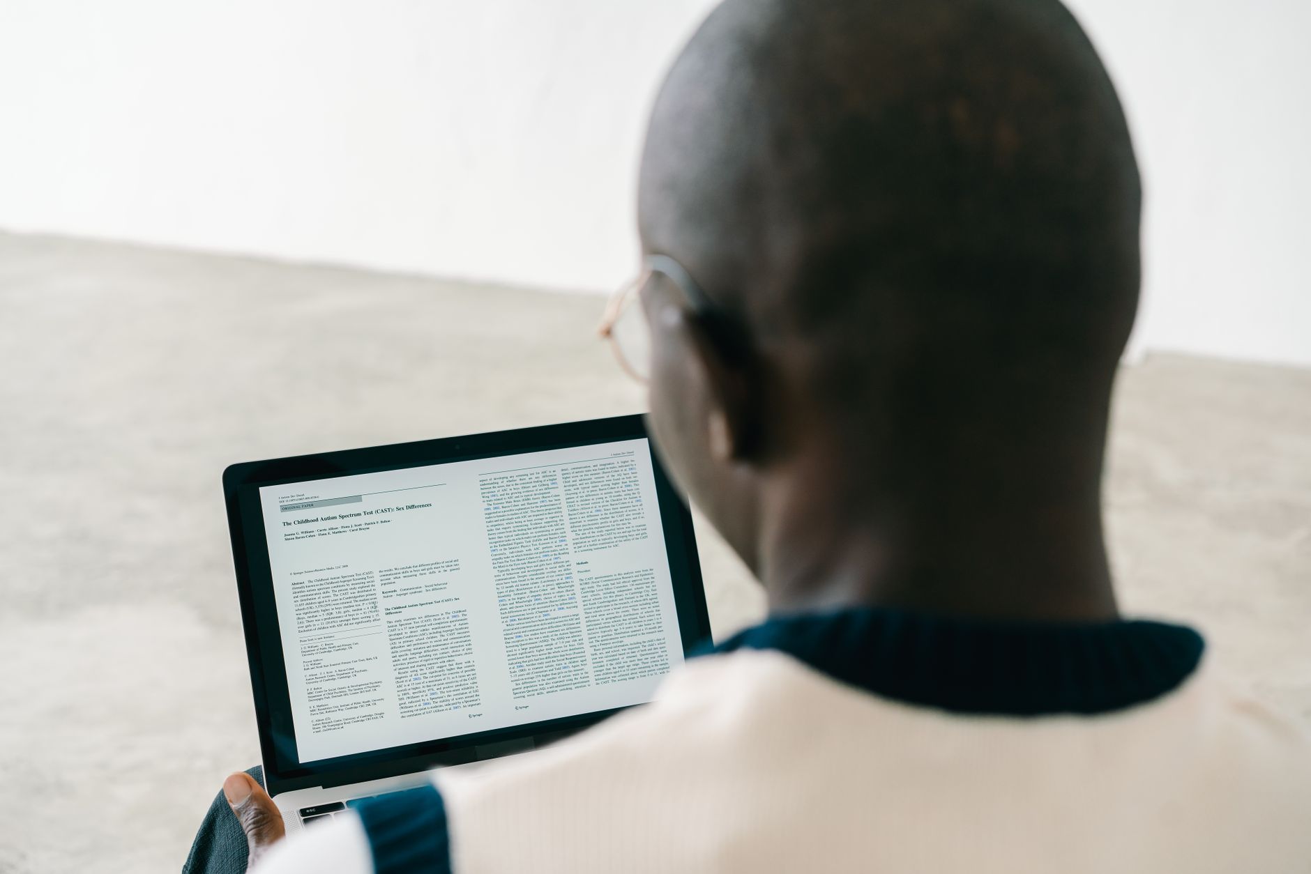 Een man leest een document op een laptopscherm in een lege ruimte