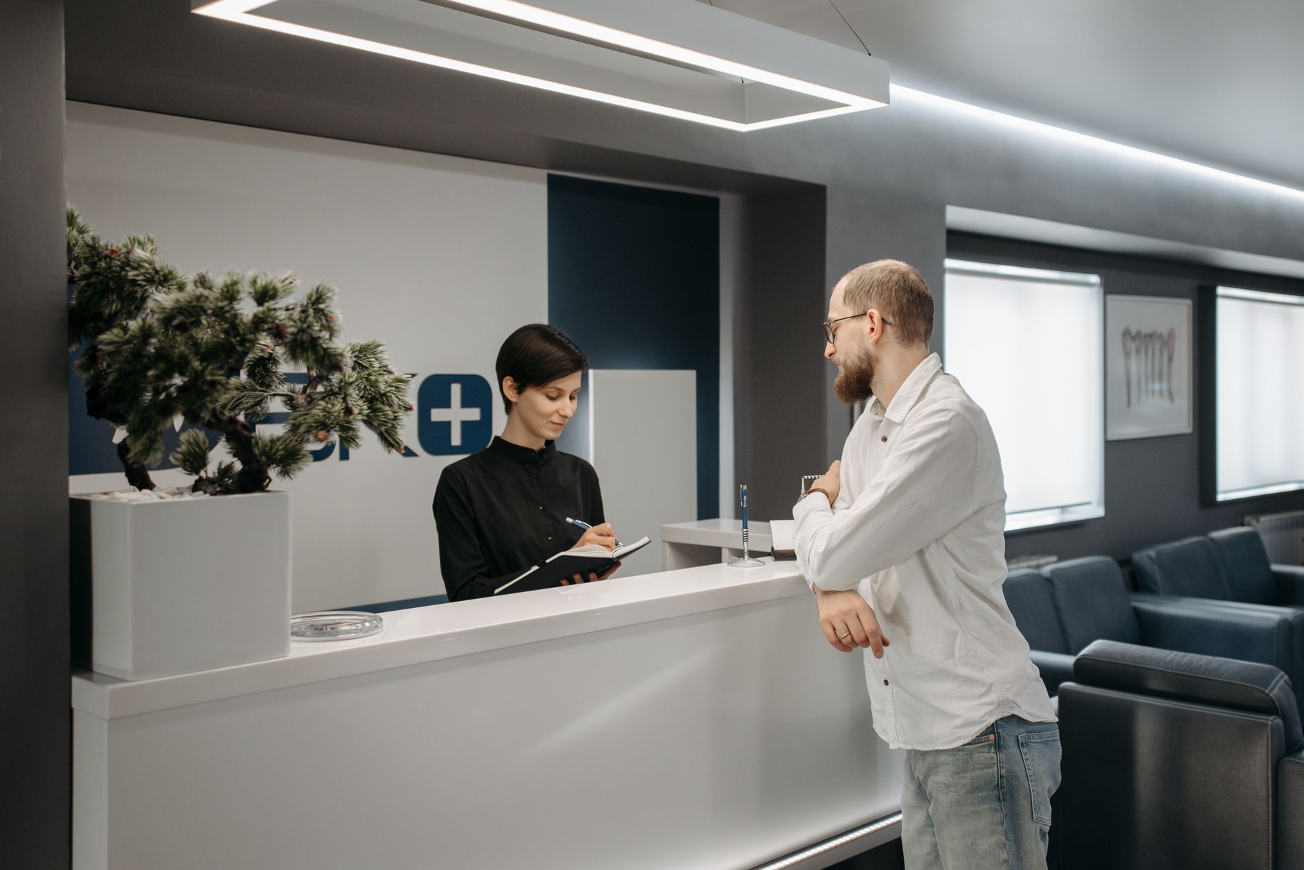 Een man overlegt met een baliemedewerker in een moderne kliniek